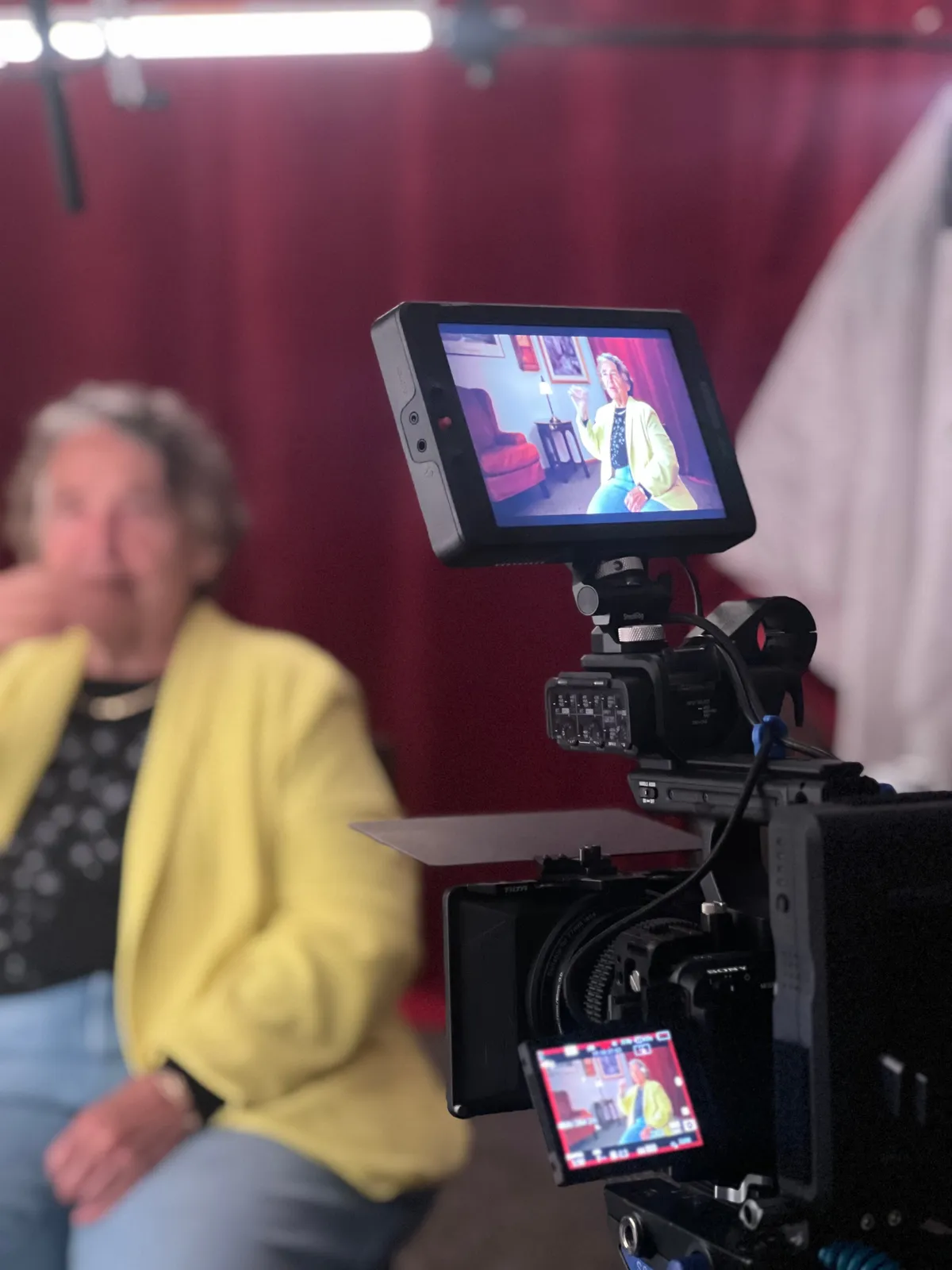 An interviewee in a yellow jacket seen on the camera monitor