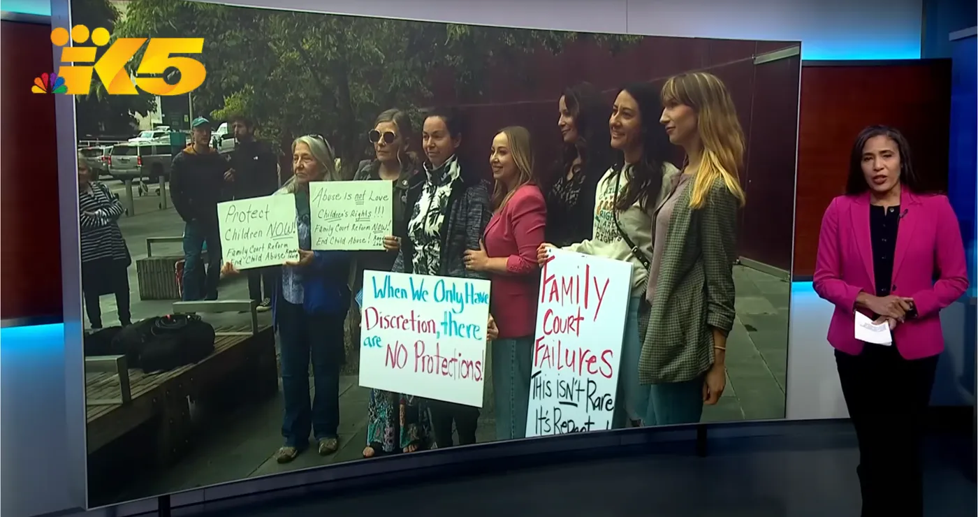 KING 5 broadcast: A4 Safety Alliance advocates hold signs reading “Family court judges need training” and “No protection” in the studio